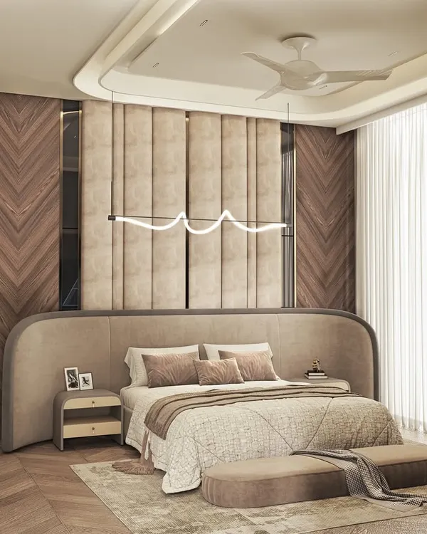 Luxury meets calm in this master bedroom retreat. I used a curved, upholstered headboard that extends along the wall, complemented by chevron-patterned wood paneling and a modern, sculptural light fixture.