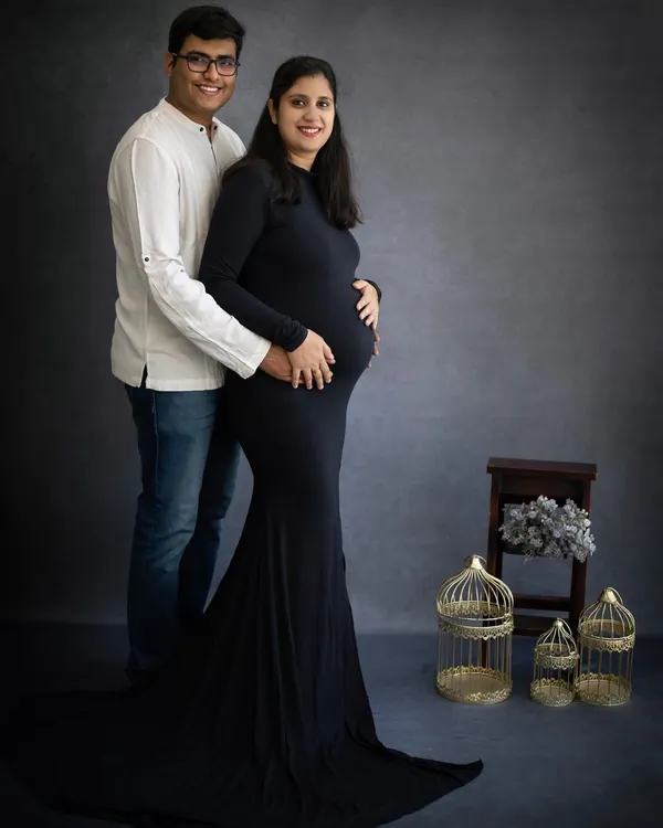A classic and elegant studio maternity portrait. The simple, dark attire emphasizes the baby bump, creating a timeless image that celebrates the beauty of pregnancy.