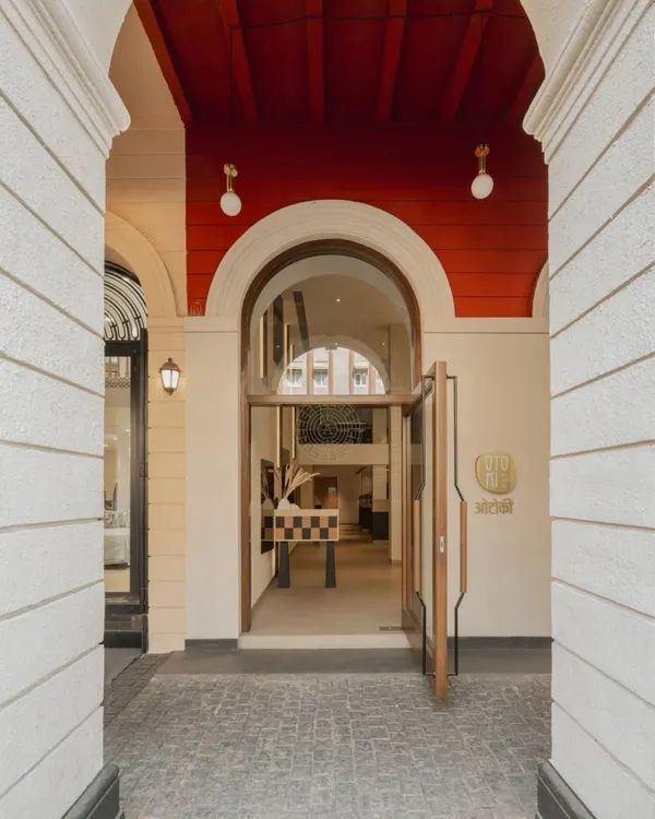The entrance to Otoki, where the building's original colonial arches frame a simple, clean wooden door, signaling the calm and minimal aesthetic within.