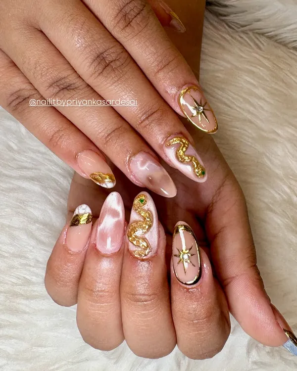 This set is pure magic. A soft nude and marble base on long almond nails provides the perfect canvas for sculpted 3D gold snakes with emerald green crystal eyes and celestial starburst accents.