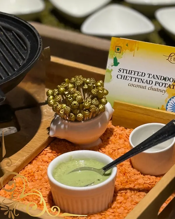 A modern take on a classic: Stuffed Tandoori Chettinad Potatoes served with a fresh coconut chutney, presented on a bed of red lentils for a dramatic effect.