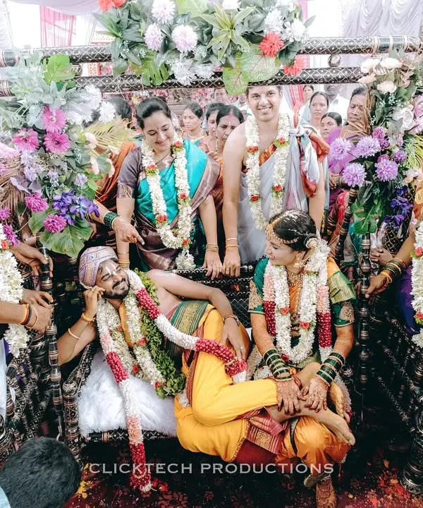A fun and candid moment from a South Indian wedding ceremony, where the groom playfully rests on a swing while surrounded by laughing family and friends.