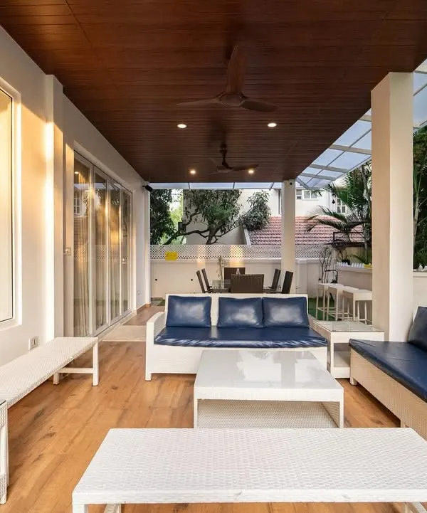 This terrace has a relaxed, coastal vibe. The white wicker furniture with deep navy cushions, a natural wood ceiling, and an open, breezy layout all come together to create a polished yet beachy atmosphere.