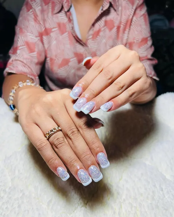 A beautiful glitter French tip on a square nail shape. This is a modern twist on a classic, combining the elegance of a French manicure with a touch of sparkle.