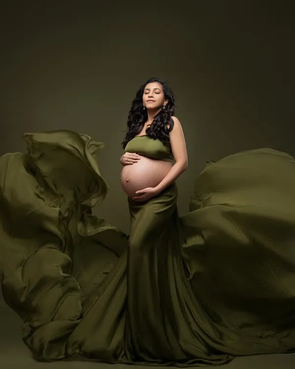 This is the essence of a luxury maternity portrait. The graceful lines of the olive gown, the soft studio lighting, and a serene expression all come together to create a truly timeless image celebrating the beauty of motherhood.