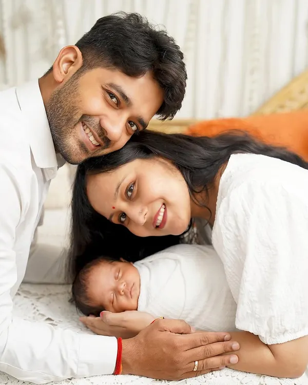 A perfect, peaceful newborn portrait. This close-up shot shows the baby sleeping soundly, nestled between his parents in a clean, white setting that emphasizes their connection.