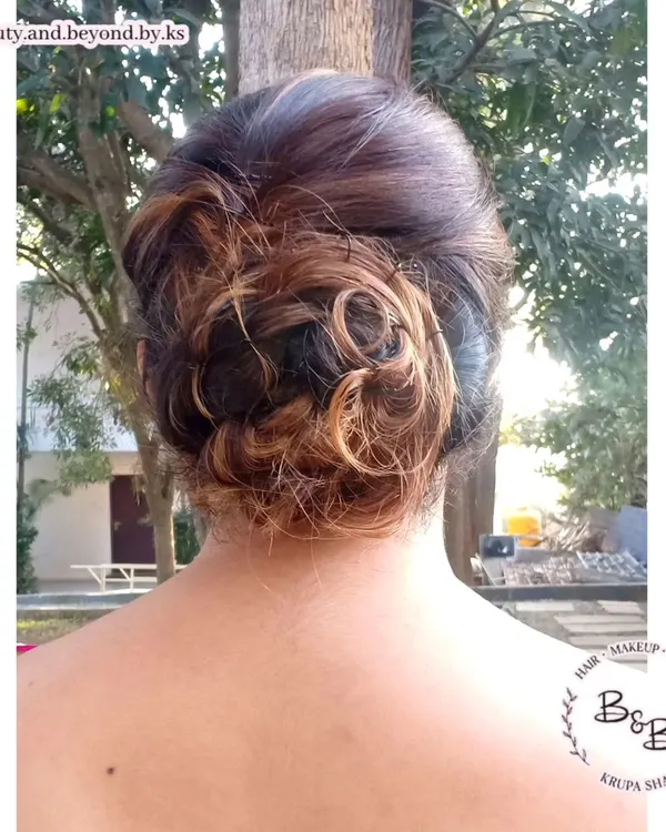 The beauty of a messy updo is in its texture. For this client, the highlights in her hair added beautiful dimension to the interwoven curls of the bun, creating a unique and modern look for her friend's wedding.