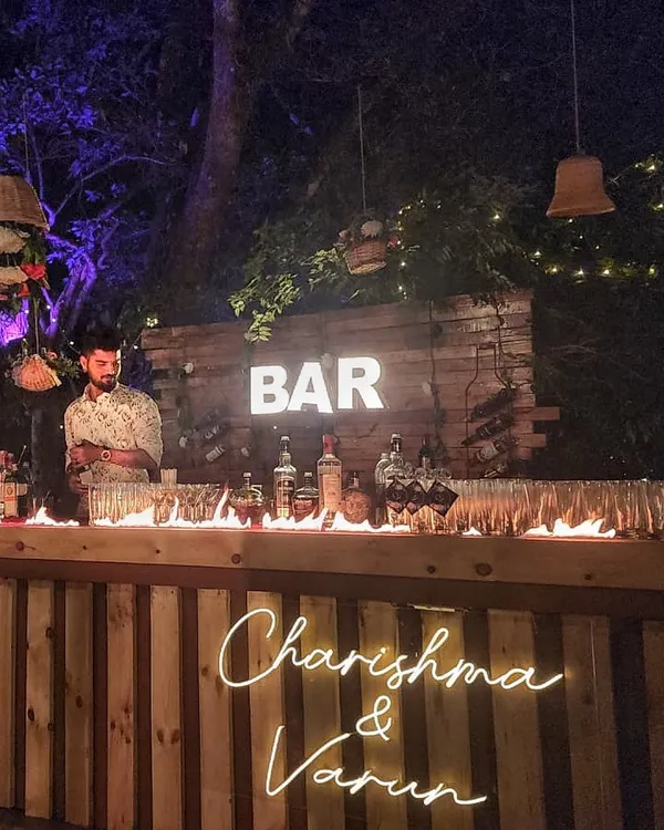 We bring the heat to your party with custom bar setups. This rustic wooden bar for Charishma and Varun's wedding featured a personalized neon sign and a dramatic, safe-to-touch fire effect along the counter.