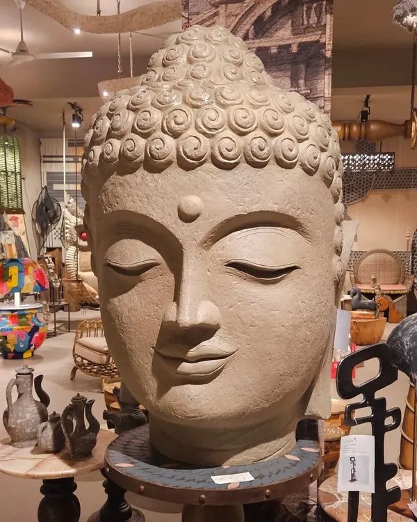 A magnificent and serene Buddha head sculpture, serving as a powerful centerpiece in our showroom. The right artifact can bring a sense of peace and grandeur to any space.