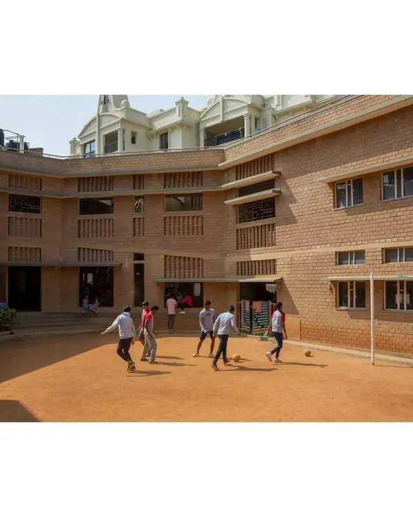 The shaded central courtyard of Buddhi School in Bengaluru, a vibrant hub for outdoor activities and play. The building's C-shaped plan was designed to create this protected space, using the structure itself to shield children from the harsh sun.