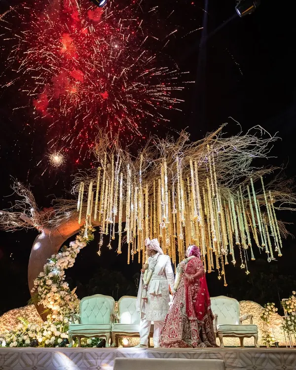 A truly explosive celebration of love under the night sky. I designed this Varmala moment with a stunning 'tree of life' mandap and a backdrop of dazzling fireworks, creating a memory that will last a lifetime.