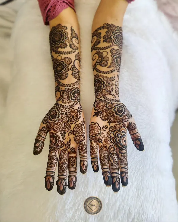 This is a perfect example of a full bridal Arabic henna for Madhia. The design features large, bold floral and paisley patterns that flow beautifully from the hands all the way up the arms.