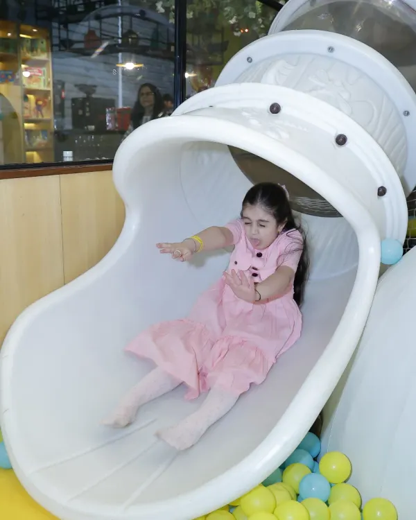 Whee! A child enjoys a fast and fun ride down our tube slide, landing safely in a colorful ball pit. It's a classic and beloved feature of our play area.