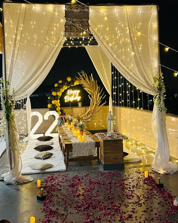 A full view of a birthday cabana on a rooftop, complete with sheer curtains, fairy lights, and a candlelit dinner table. This shows how I can create a private, romantic world for your special occasion.
