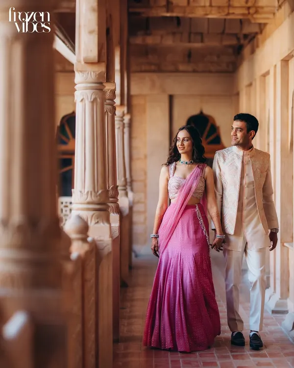 Kanav and Saloni share a moment while walking through a sunlit corridor at Khimsar Fort. The repeating pillars create a beautiful sense of depth and frame them perfectly.