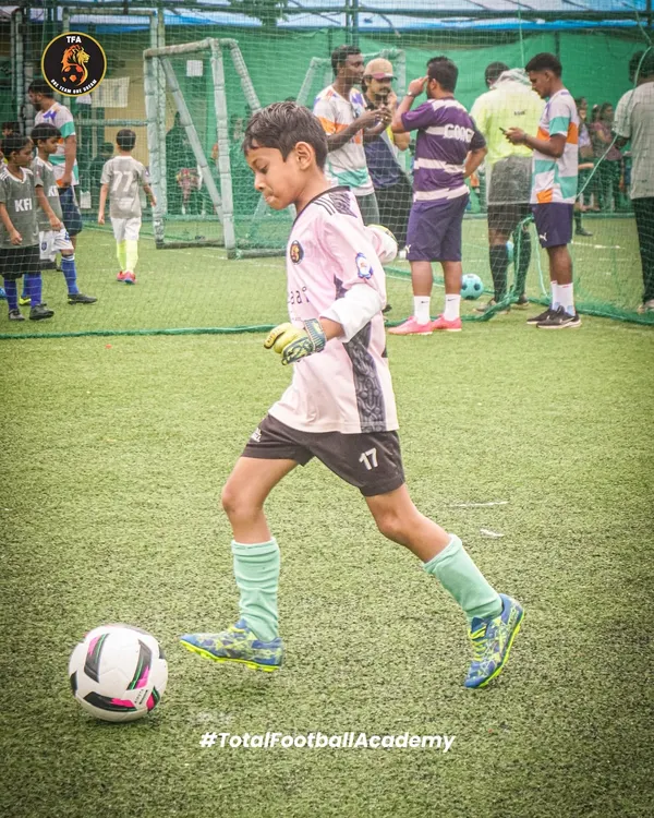 A young goalkeeper in control, dribbling the ball upfield. We train every player to be comfortable and skilled with the ball at their feet.
