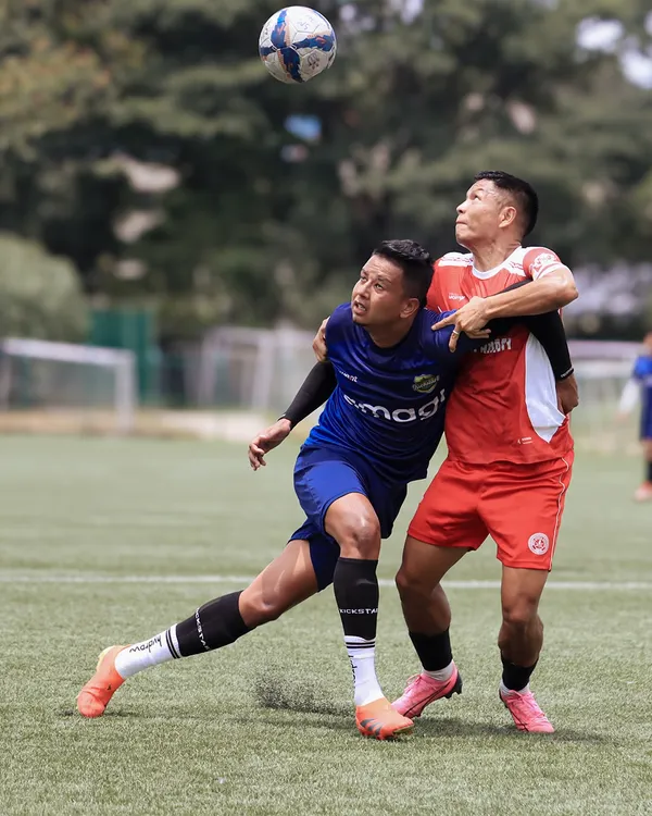An intense aerial duel between two players, both committed to winning the header in a moment of peak action.