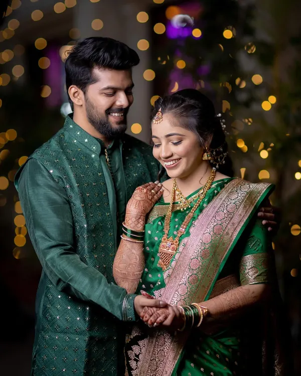 A joyful and candid moment from a ring ceremony. The genuine smiles and beautiful traditional attire are captured against a backdrop of sparkling lights.