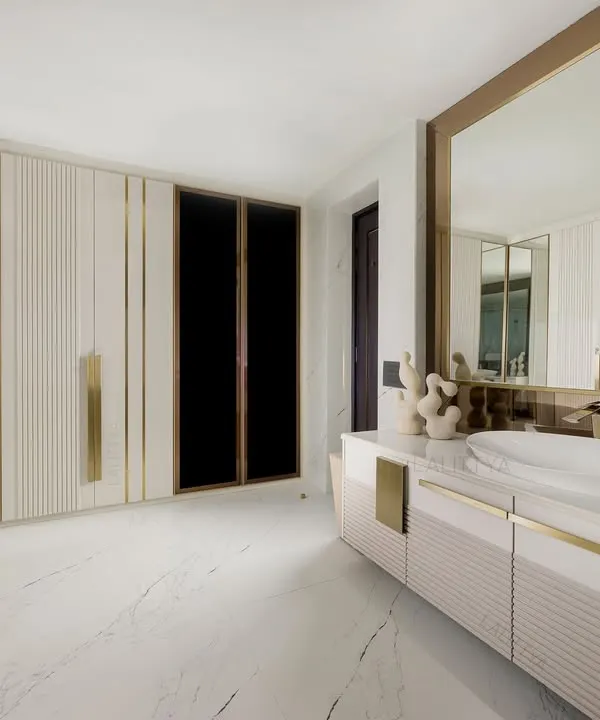 A master suite designed for slow rituals. The walk-in wardrobe, with its mirrored and fluted doors, flows seamlessly into the master washroom. The curved vanity, vessel sink, and brass accents create a space that feels both private and indulgent.