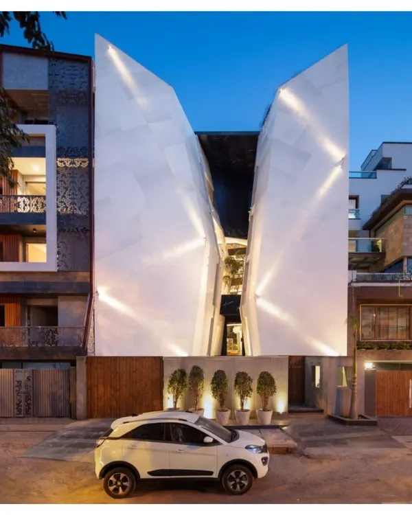 Our Cleft House project in New Delhi, conceived as a breached monolith. The faceted white marble facade creates a dramatic play of light and shadow at dusk, while the central void provides natural ventilation and a private social courtyard at its heart.