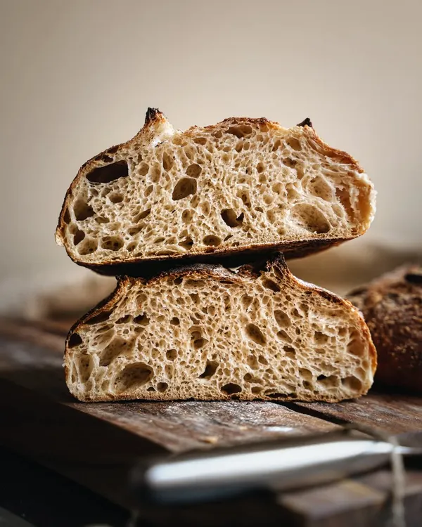 The beauty of a perfect sourdough loaf is in its details. This cross-section shot highlights the open, airy crumb and the beautiful "ear" on the crust.