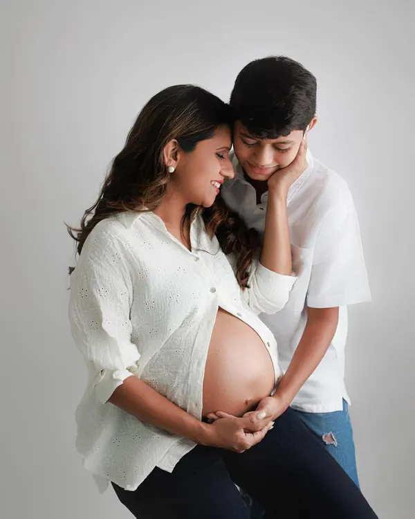 Welcoming a new chapter. This beautiful maternity portrait shows an expecting mother and her son sharing a tender moment, excited for the new arrival.