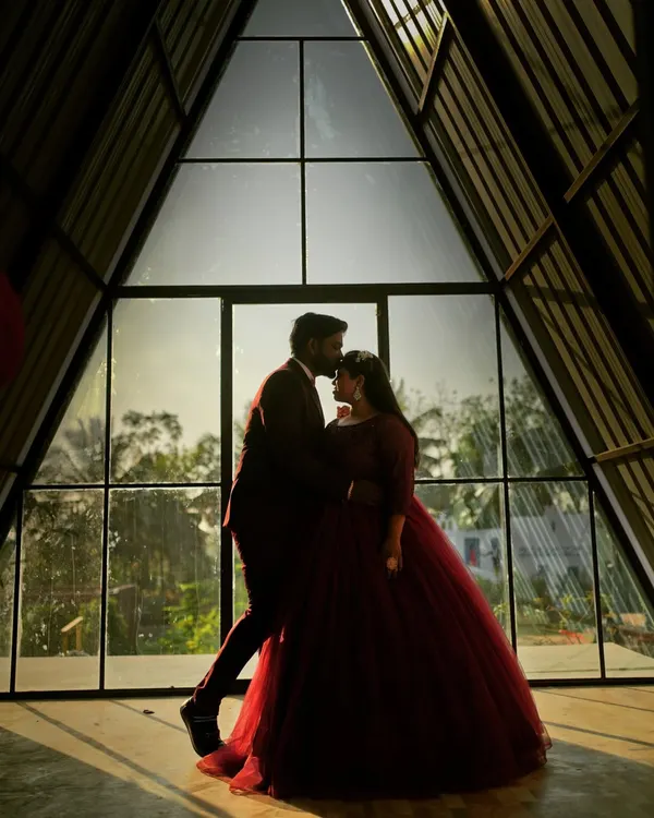 A silhouette of a couple against a modern A-frame window, creating a beautifully artistic and intimate pre-wedding photograph.