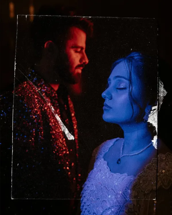 An artistic, experimental portrait using colored gels and a glass reflection effect to create a dreamy, futuristic image of a couple during their sangeet shoot.