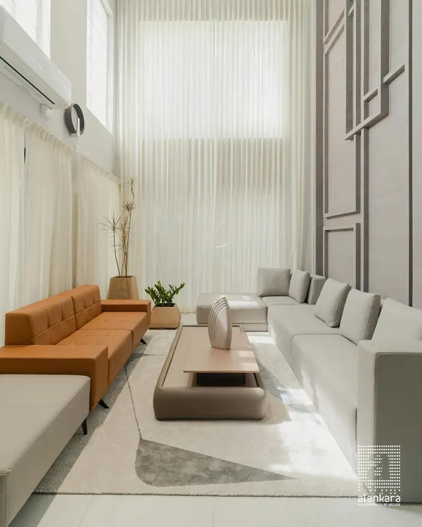 This is where grand vision meets meticulous execution. In this double-height living room, I used floor-to-ceiling sheer curtains to harness the abundant natural light, creating an airy, expansive feel. The custom-designed sectional sofas in contrasting neutral and warm tones are crafted for both luxurious comfort and sophisticated entertaining.