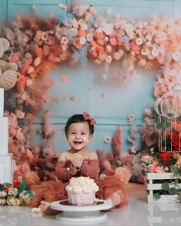 A beautiful first birthday celebration with a floral-themed cake smash. This setup includes a stunning pastel flower arch, 'ONE' blocks, and cuddly teddy bears to create a magical setting for this special milestone.