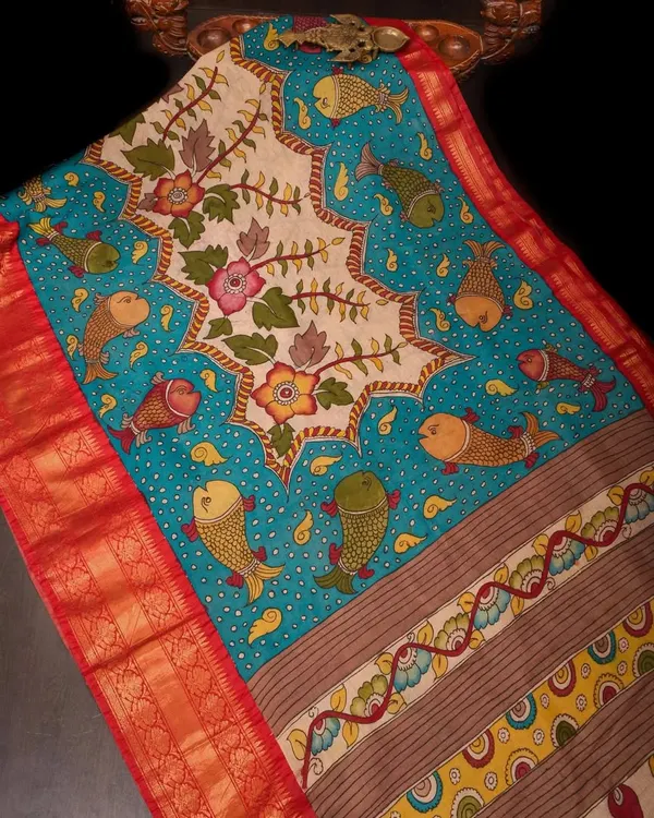 This Pen Kalamkari saree is a whimsical masterpiece, featuring hand-painted fish motifs swimming in a sea of blue. The central panel showcases intricate floral designs, all drawn by hand with natural dyes.