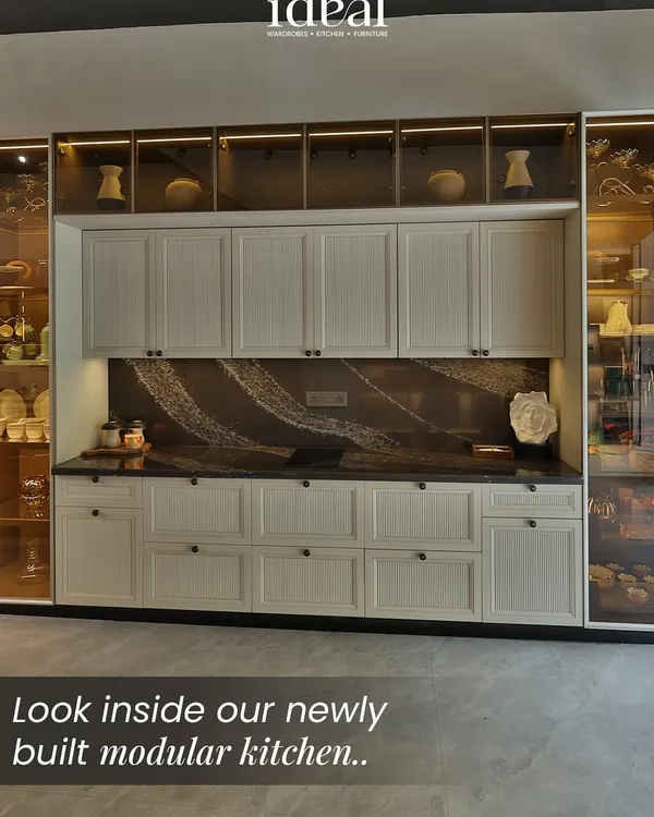 A full view of a timeless kitchen design, featuring classic white fluted cabinetry paired with a dramatic, veined marble backsplash. The glass-fronted upper cabinets with internal lighting add a touch of display elegance, creating a balanced and sophisticated look.
