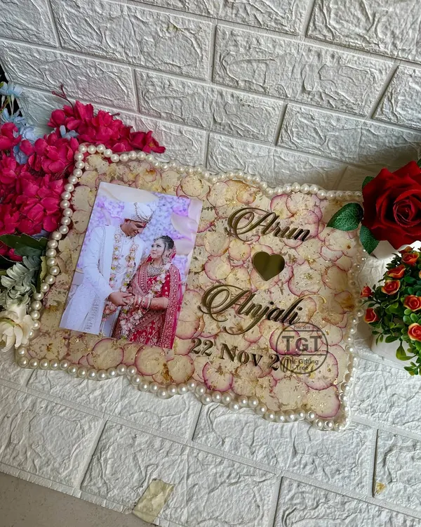 A beautiful 12x16 inch rectangular resin frame preserving a couple's wedding photo and varmala petals. The border is lined with pearls from the original garland.