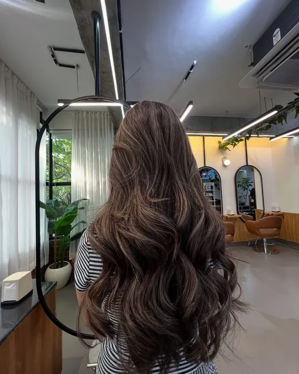 A full view of this gorgeous brunette balayage, styled with loose waves to showcase the seamless blend of light and dark tones. This is a perfect example of a low-maintenance, high-impact lived-in color.