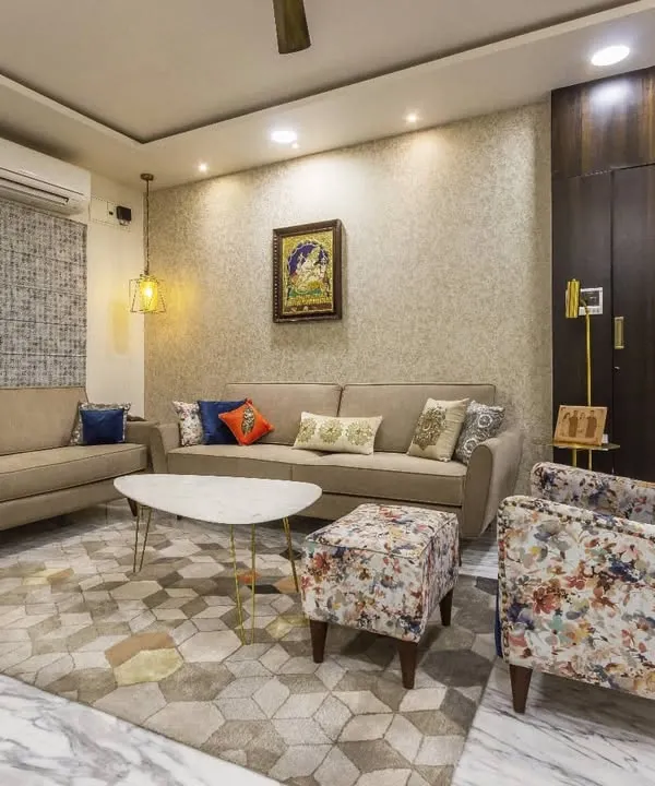 This living room is built on a neutral foundation with a comfortable beige sofa, allowing the accent pieces to shine. A bold, floral-printed wingback chair and colorful cushions add personality, while a geometric rug ties the entire seating arrangement together.