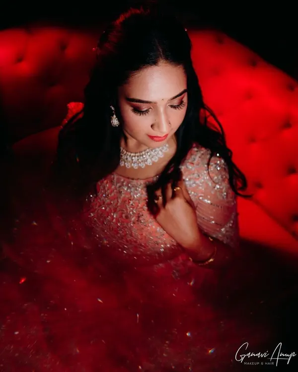 A dramatic, high-fashion shot of the bride's reception look. The focus is on her sparkling gown and the glamorous makeup, featuring a smokey eye and a bold red lip.