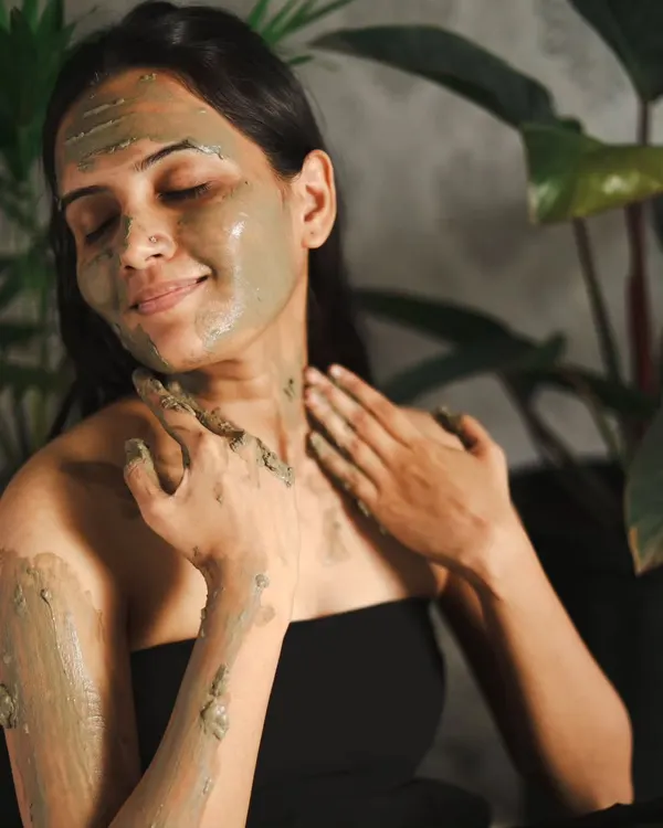 A perfect shot for a skincare campaign, showing a model enjoying the feeling of a clay mask. Her serene expression and the natural setting convey a sense of wellness and self-care.
