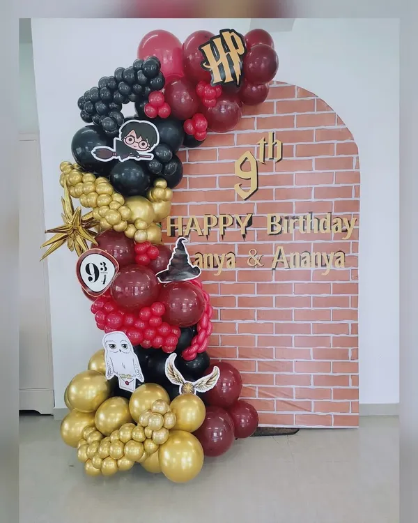 Welcome to Hogwarts! This magical Harry Potter themed backdrop is perfect for a 9th birthday. It features a brick wall arch reminiscent of Platform 9 3/4, surrounded by an organic balloon garland in Gryffindor colors with themed cutouts like Hedwig and the Golden Snitch.
