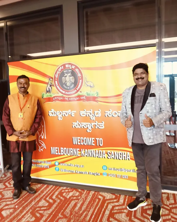 At the Melbourne Kannada Sangha event in Australia. I am standing next to the welcome banner, all set for the program to begin.