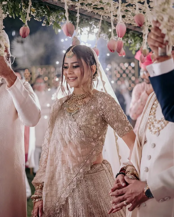 The bride's entry is a magical moment. Her soft, glowing makeup and elegant hairstyle are designed to look breathtaking as she walks towards her new beginning, framed by a beautiful floral canopy.