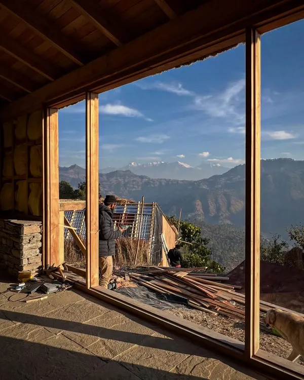 A view from inside one of our guesthouses in Vasudev, Uttarakhand. The large timber-framed window is designed to perfectly capture the breathtaking panorama of the Nanda Devi and Panchachuli peaks, making the landscape the central focus of the interior space.
