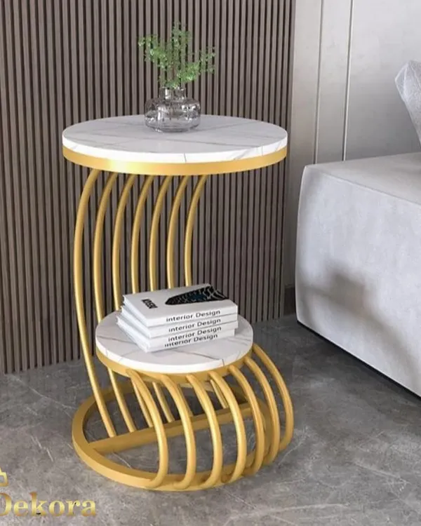 This C-shaped side table features a distinctive ribbed metal frame in a gold finish, supporting two marble-finish surfaces. Its tiered design is perfect for placing next to a sofa, providing convenient storage for books and decor.