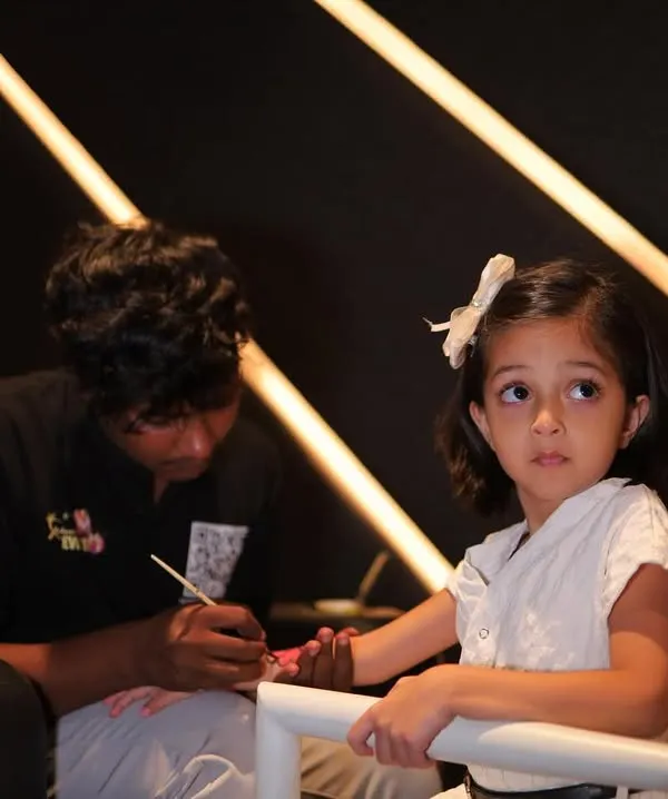 One of our talented artists carefully painting a temporary tattoo on a young guest's arm. We are professional and great with kids.