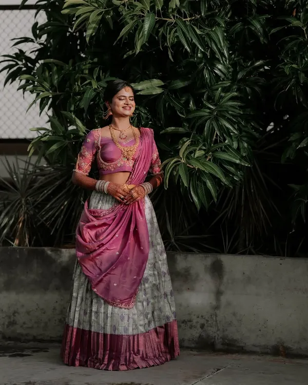 A happy client looking beautiful in a grey and pink Langa Dhawani. This traditional South Indian outfit is a popular choice for coming-of-age ceremonies and engagement functions.