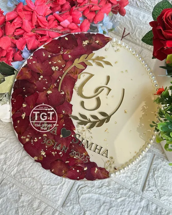 A beautiful 10-inch round resin plaque preserving red rose petals in a crescent moon shape. This piece features a custom couple logo, names, and wedding date in gold on a shimmery ivory base.
