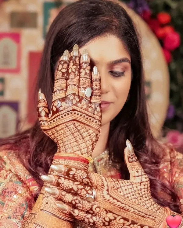 The final result: a happy bride with her stunning, dark-stained mehandi. This is a beautiful pose to capture the intricate details on the palm and fingers.