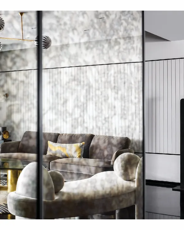 Reflections are a powerful tool in design. Here, an antique mirrored wall expands the living room of this seaside apartment, creating an illusion of depth while softly echoing the light and movement in the space. The effect is a luxurious, layered interior that feels both grand and intimate.