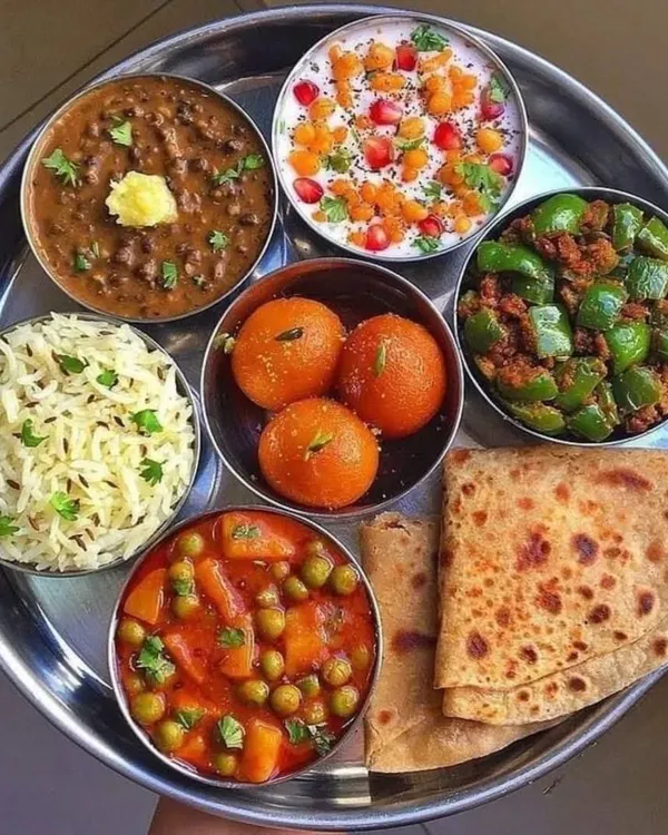 This is what a feast from my kitchen looks like. A complete, balanced thali featuring our creamy Dal Makhani, flavorful Aloo Mutter, spicy Shimla Mirch Bhaji, refreshing Boondi Raita, soft Ghee Parathas, fragrant Jeera Rice, and sweet Gulab Jamuns. It’s a plate full of comfort and joy.
