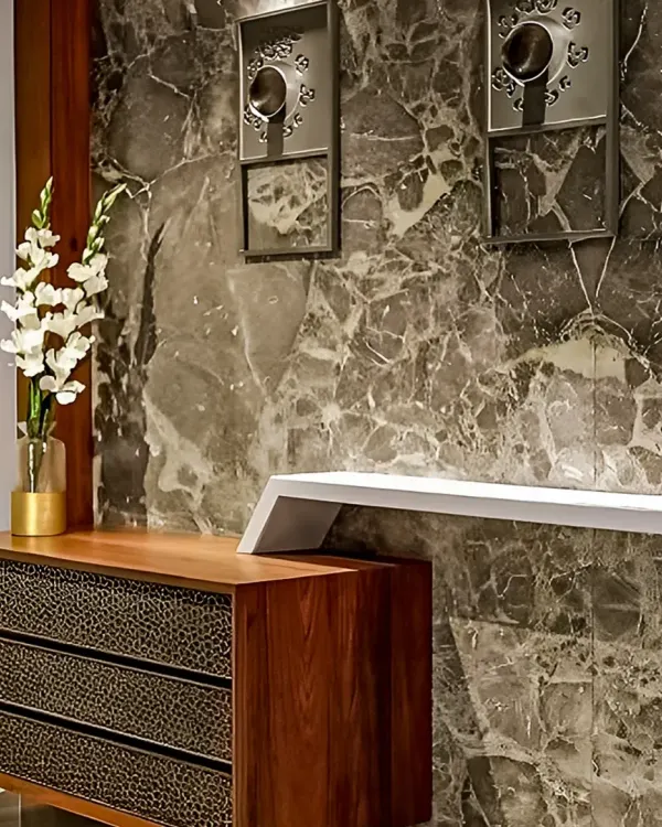 A close-up view of a luxury foyer design. We paired a dramatic, dark marble feature wall with a custom wooden console that has textured drawer fronts, creating a powerful first impression.