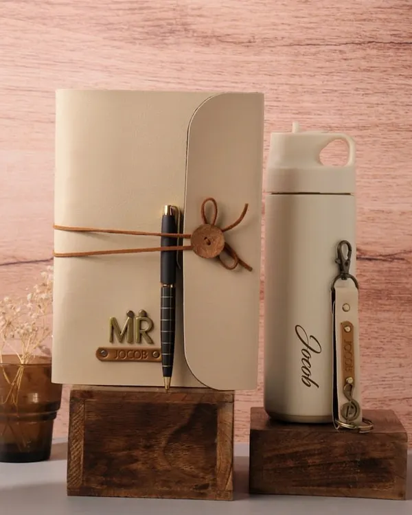 This beautifully styled gift set features a personalized cream-colored diary with a pen and a matching insulated tumbler engraved with the name "Jacob." It's a thoughtful and practical gift for any occasion.
